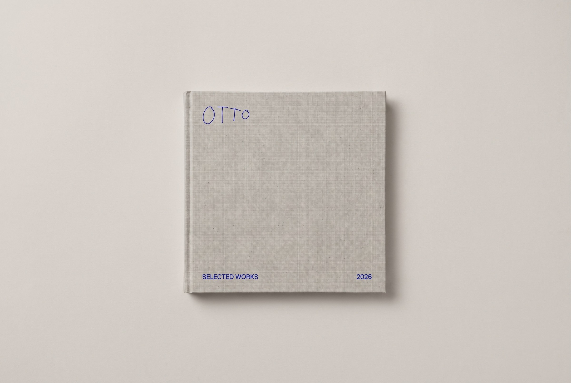 A square linen-bound book, ‘OTTO — Selected Works 2026’, alone on a pale field